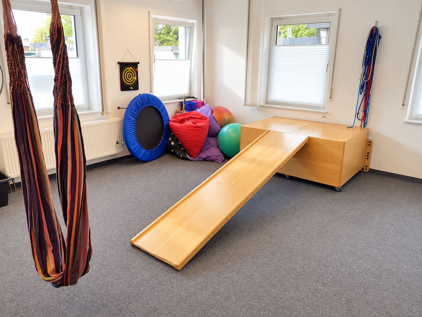 Therapieraum der Praxis in Plettenberg mit Hängeschaukel, Rutsche und Trampolin